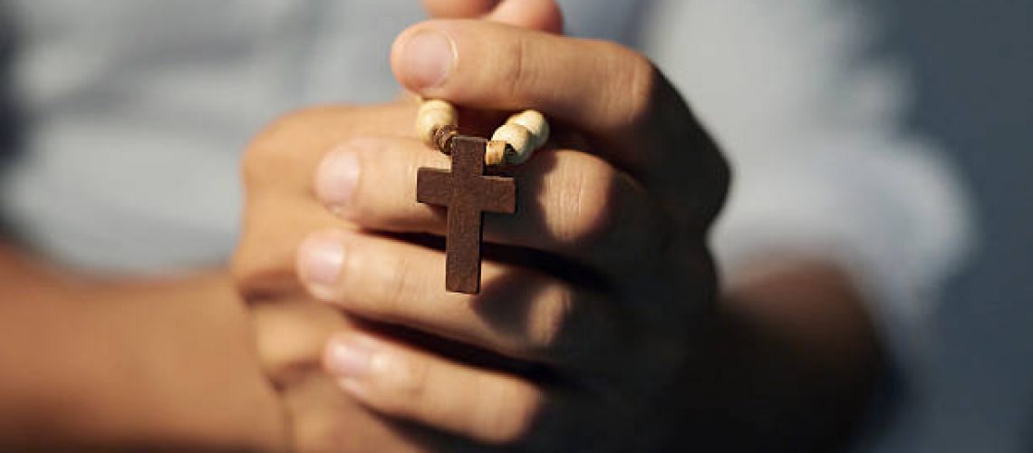 Cropped shot of a man's hands holding a rosary